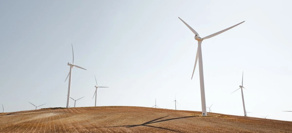 Turbina wiatrowa stojąca wysoko na obszernym polu w ecoregionie, zrównoważony źródło energii dla publicznej użyteczności.